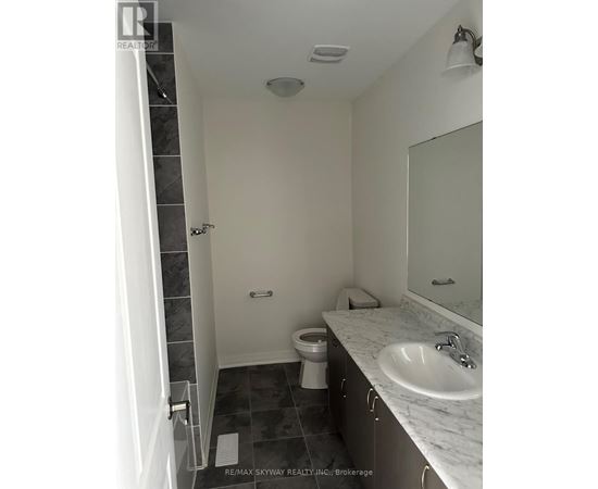 A bathroom with a toilet, sink, and mirror.