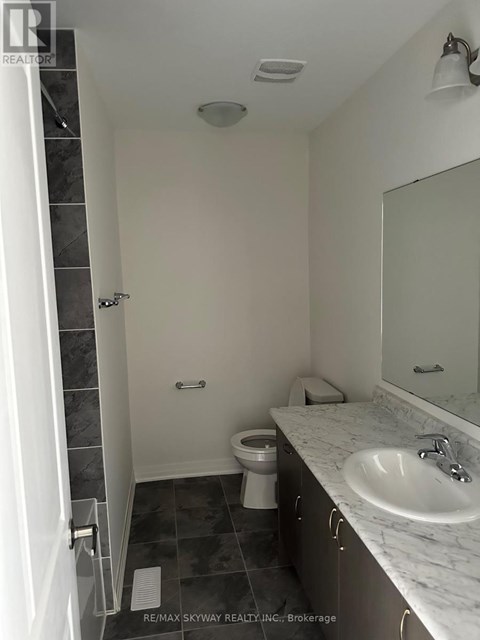 A bathroom with a toilet, sink, and mirror.