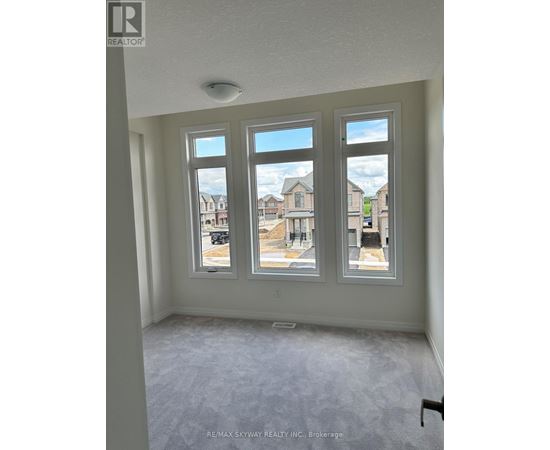 A room with three windows showing an outdoor view of a residential area.