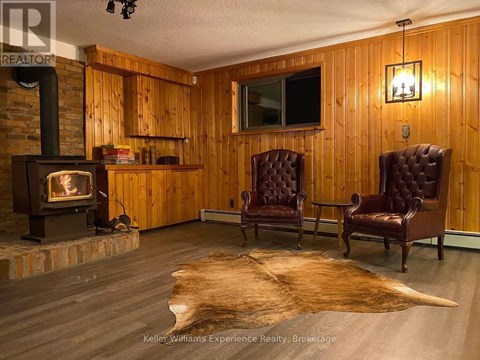 A living room with a wood stove and two leather chairs.