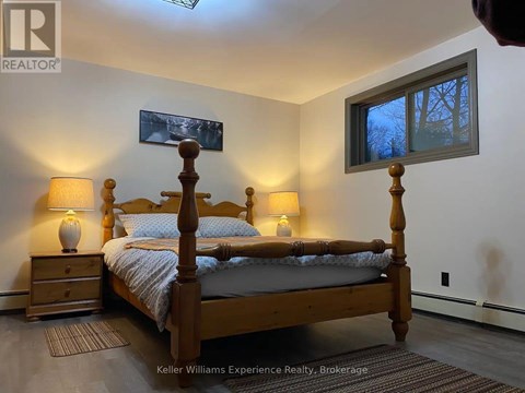 A bedroom with a bed, nightstands, and a window.