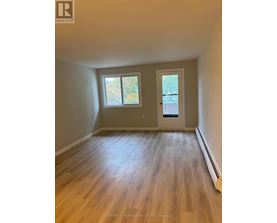 A room with wooden floors and a door leading to a balcony.
