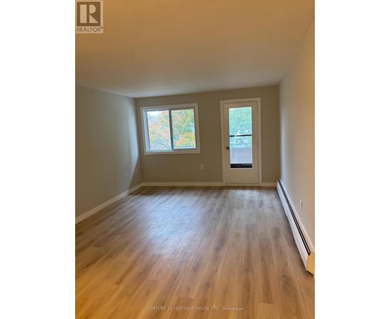 A room with wooden floors and a door leading to a balcony.