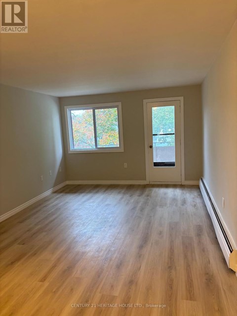 A room with wooden floors and a door leading to a balcony.