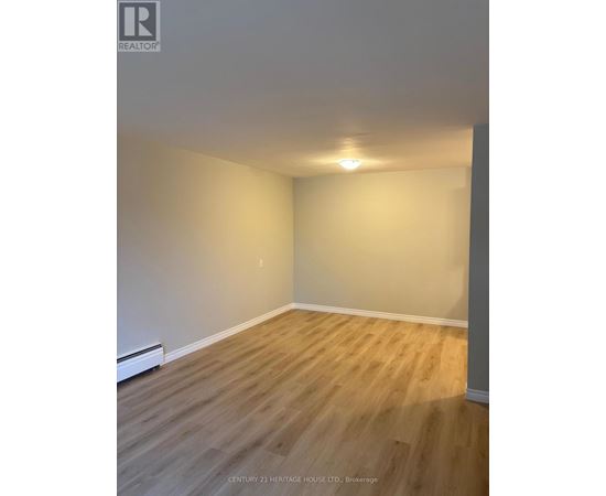 A room with wooden flooring and white walls.
