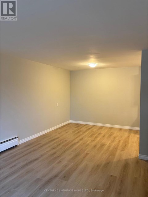 A room with wooden flooring and white walls.