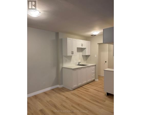 A kitchen with white cabinets and a wooden floor.