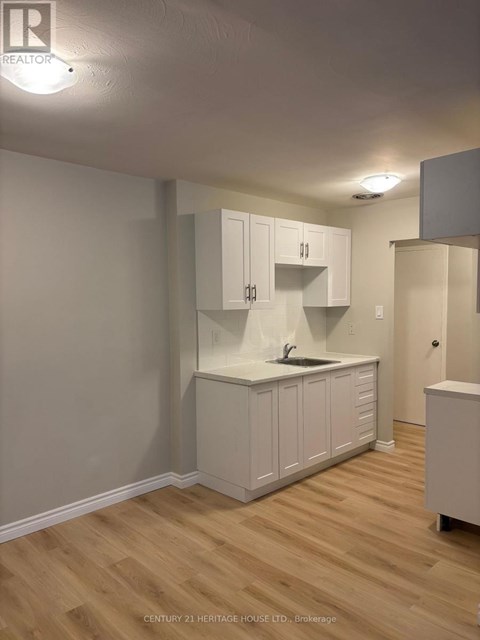 A kitchen with white cabinets and a wooden floor.