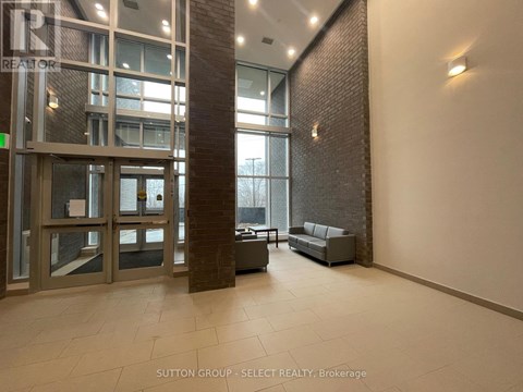 A hallway with a glass door and a brick pillar.