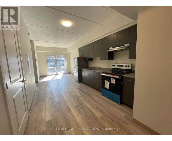 A kitchen with wood flooring and a refrigerator.