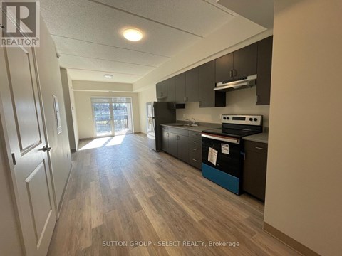 A kitchen with wood flooring and a refrigerator.