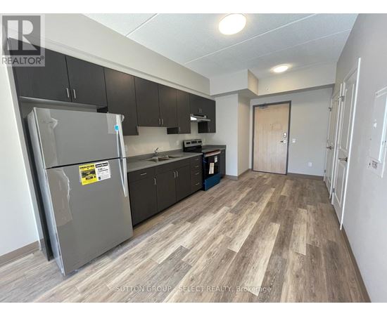 A kitchen with a refrigerator, cabinets, and a countertop is shown.