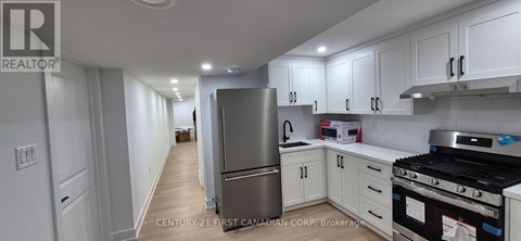 A kitchen with white cabinets and a stainless steel refrigerator.
