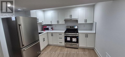A kitchen with a stainless steel refrigerator and white cabinets.