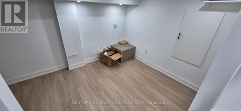 A room with wooden flooring and white walls, with a cardboard box on the floor.