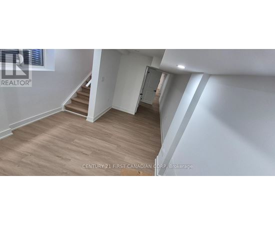 A spacious room with wooden flooring and white walls.