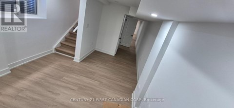 A spacious room with wooden flooring and white walls.