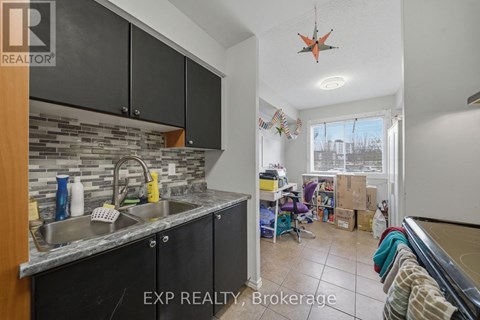 A kitchen with black cabinets and a stone backsplash is for sale.