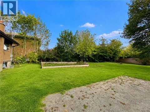 A backyard with a gravel area and a wooden fence.