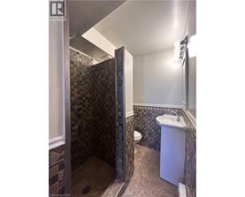 A bathroom with a tiled shower and a white sink.
