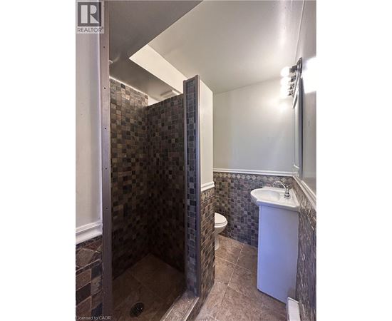 A bathroom with a tiled shower and a white sink.