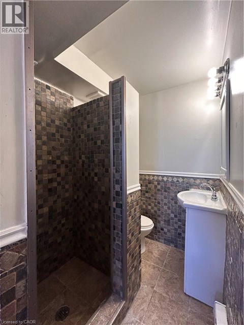 A bathroom with a tiled shower and a white sink.