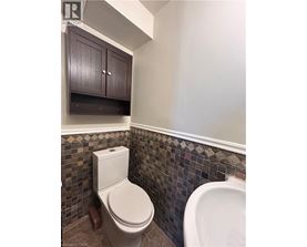 A white toilet in a bathroom with brown cabinets and a tiled wall.