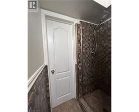 A white door is on the left of a tiled shower.