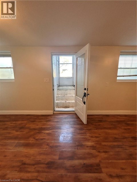 A room with a wooden floor and a door leading to a balcony.