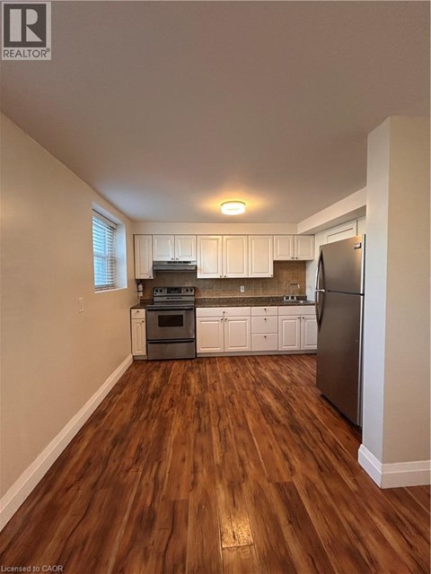 A kitchen with a refrigerator, oven, and cabinets.
