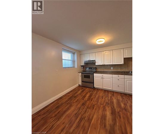A kitchen with white cabinets and a wooden floor.
