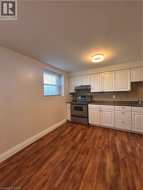 A kitchen with white cabinets and a wooden floor.