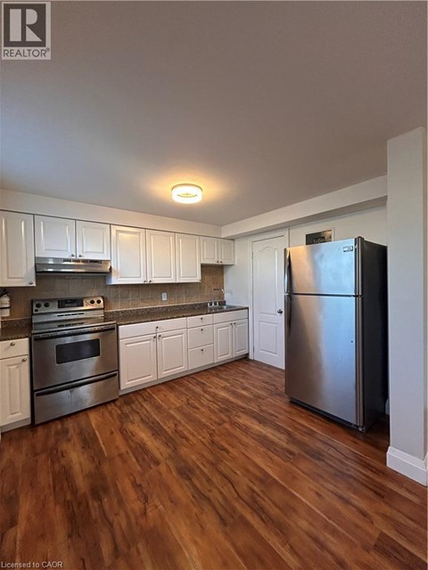 A kitchen with white cabinets and a stainless steel refrigerator.