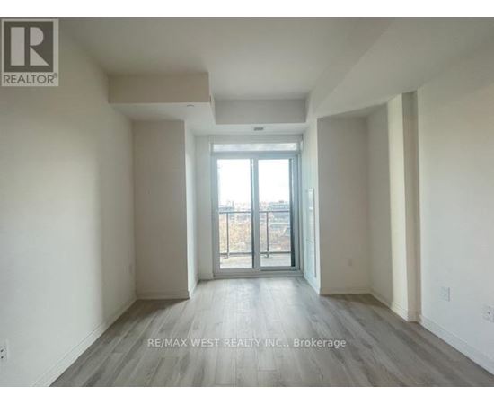 A spacious room with a sliding glass door leading to a balcony.