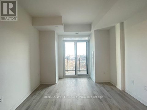 A spacious room with a sliding glass door leading to a balcony.