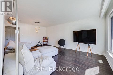 A living room with a white couch and a black TV on a stand.