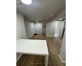 A white table is in the middle of a room with wood floors and white walls.