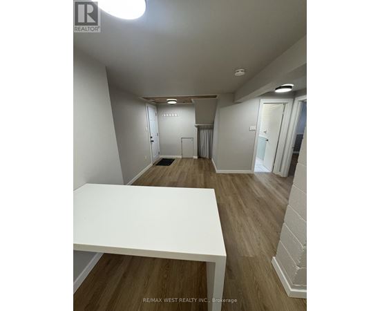 A white table is in the middle of a room with wood floors and white walls.