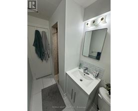 A white bathroom with a sink, mirror, and towel rack.