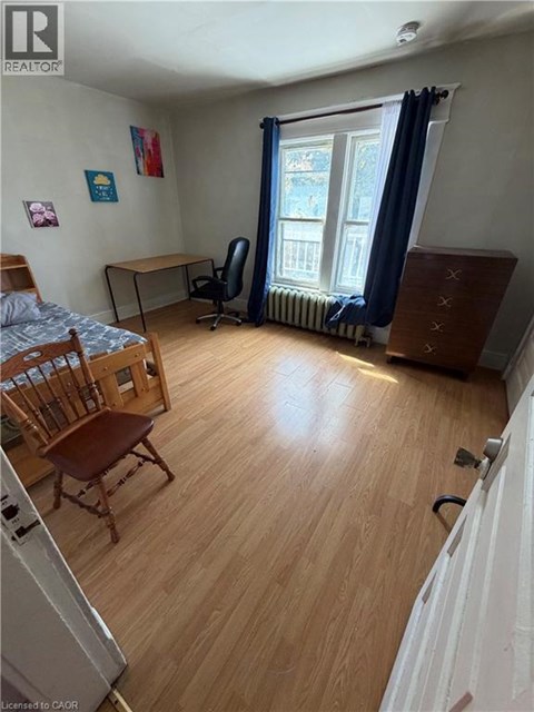 A bedroom with a bed, desk, chair, and a window with curtains.