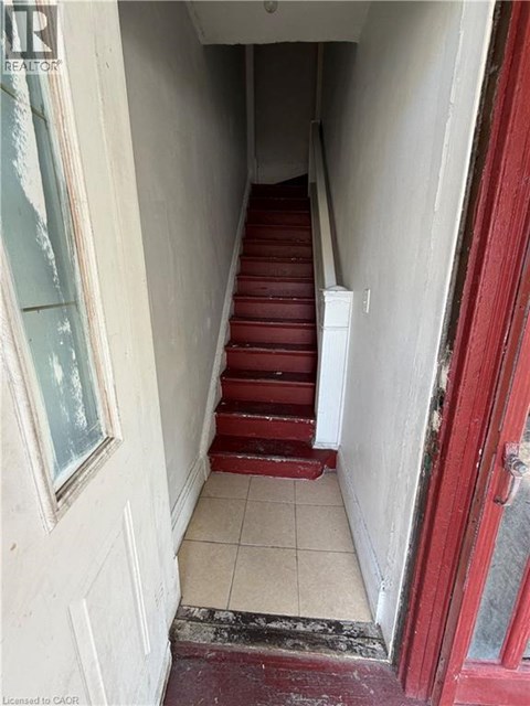 A hallway with red stairs and a white door.