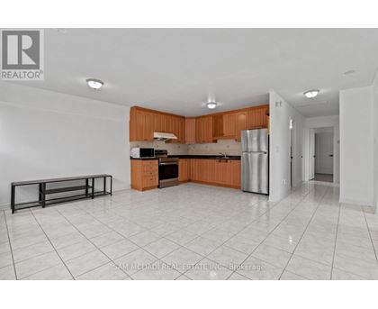 A kitchen with white tiled floors and wooden cabinets.