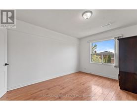 A room with a window showing a house and trees outside.