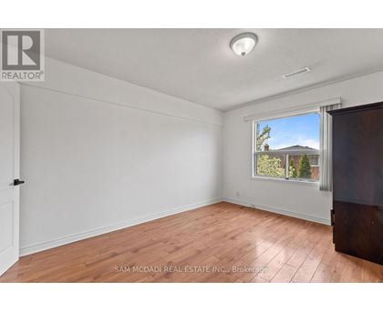 A room with a window showing a house and trees outside.