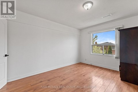 A room with a window showing a house and trees outside.