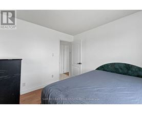 A bedroom with a bed, dresser and a door.