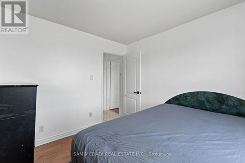 A bedroom with a bed, dresser and a door.