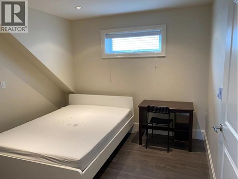 A bedroom with a bed, desk, and chair.