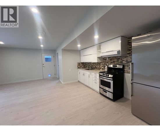 A modern kitchen with stainless steel appliances and a stone backsplash.