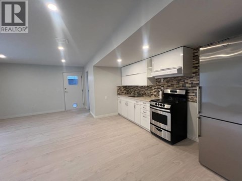 A modern kitchen with stainless steel appliances and a stone backsplash.